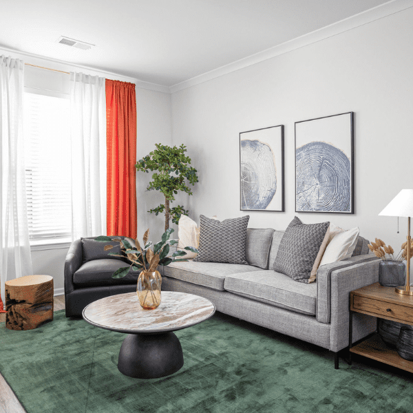 A modern apartment building with beige and rust-colored walls. The building features several balconies with glass railing and beige supports. The photo is taken on a clear, sunny day, highlighting the clean lines and contemporary design of the structure.